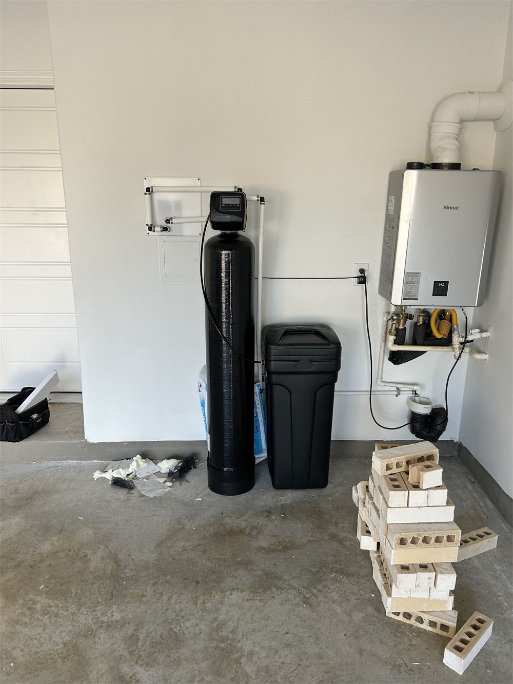 Water treatment tank installed alongside a tankless water heater